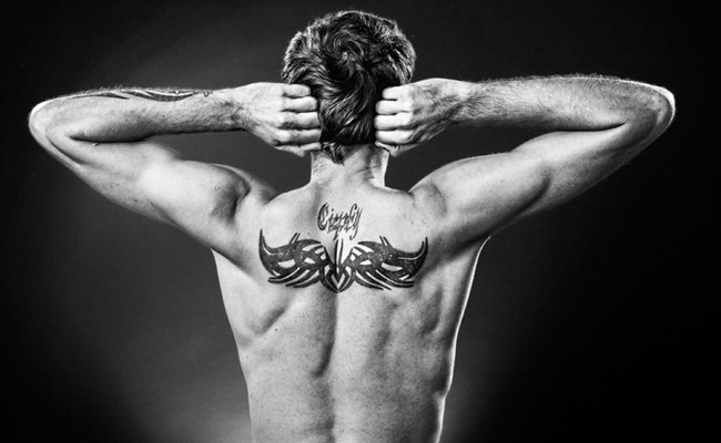 Man showing tatoo on his back made in studio
